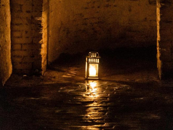 Candle casting light across a darkened space