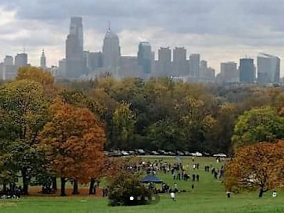 Image of a park in the fall with the Philadelphia skyline in the background