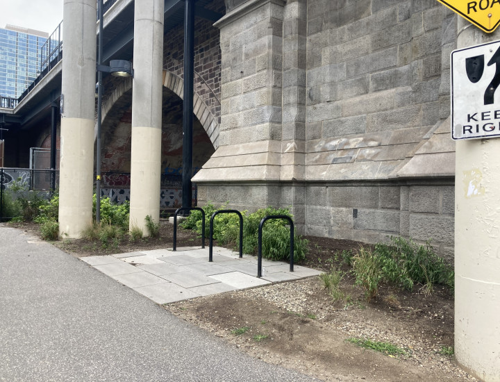 Black bicycle rack installed in cement with Market Street Bridge in the background