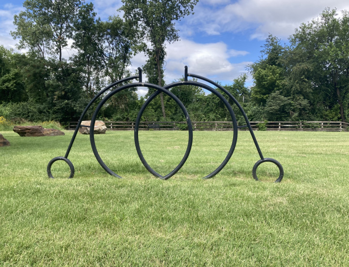 Bike rack in the shape of two pennyfarthings, situated in greenery