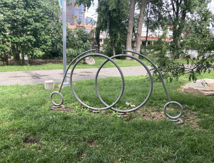 Bike rack in the shape of two pennyfarthings, situated in greenery