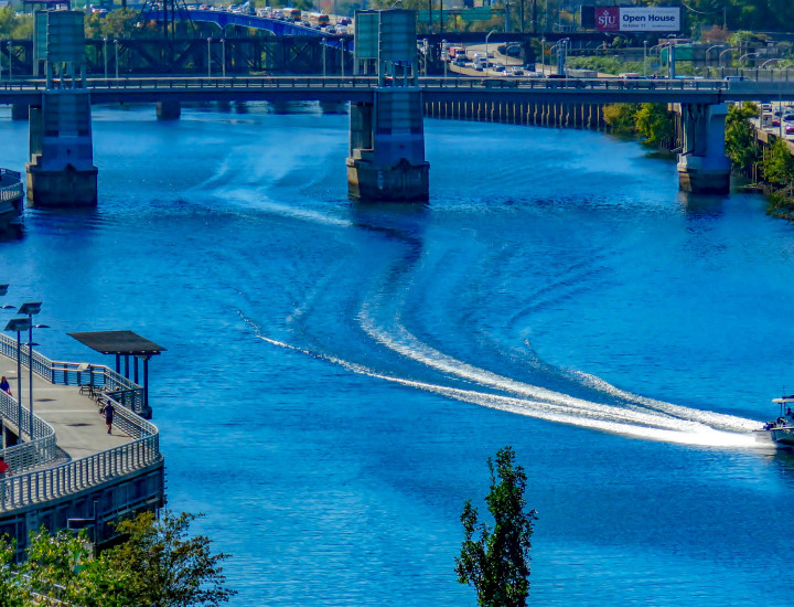 Boat and its wake coming up the river along the boardwalk on a sunny day