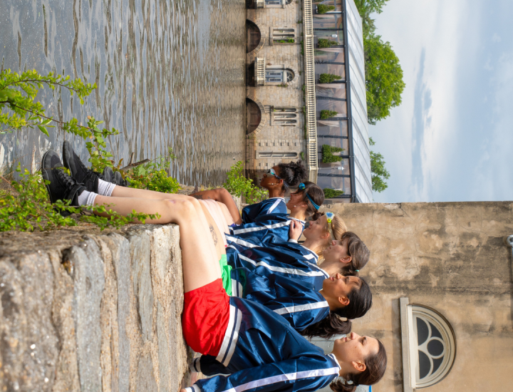 sideways image of dancers seated on a wall above the Schuylkill River
