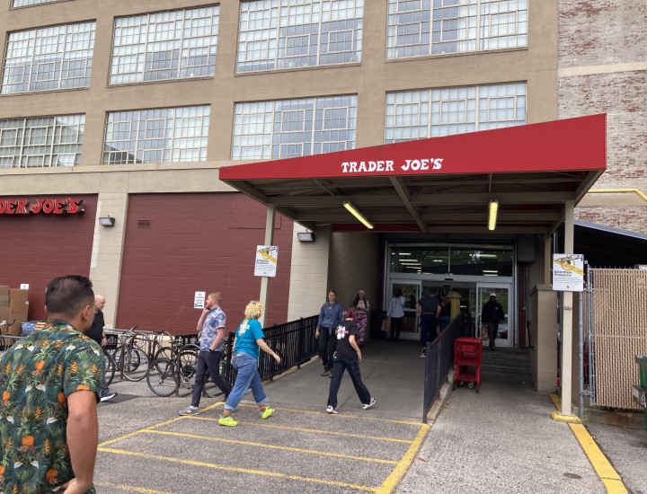 Entrance to Trader Joes, with people walking up the ramp to the automatic doors