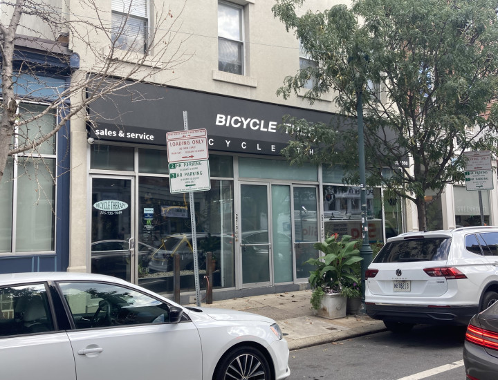 Exteriorof Bicycle Thief, semi-obscured by a tree and passing cars