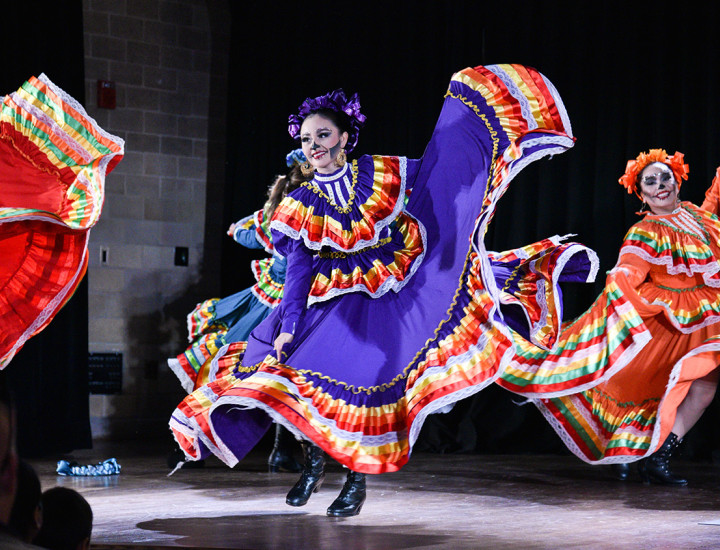 Dancers in colorful dresses and Dia de los Muertos face paint